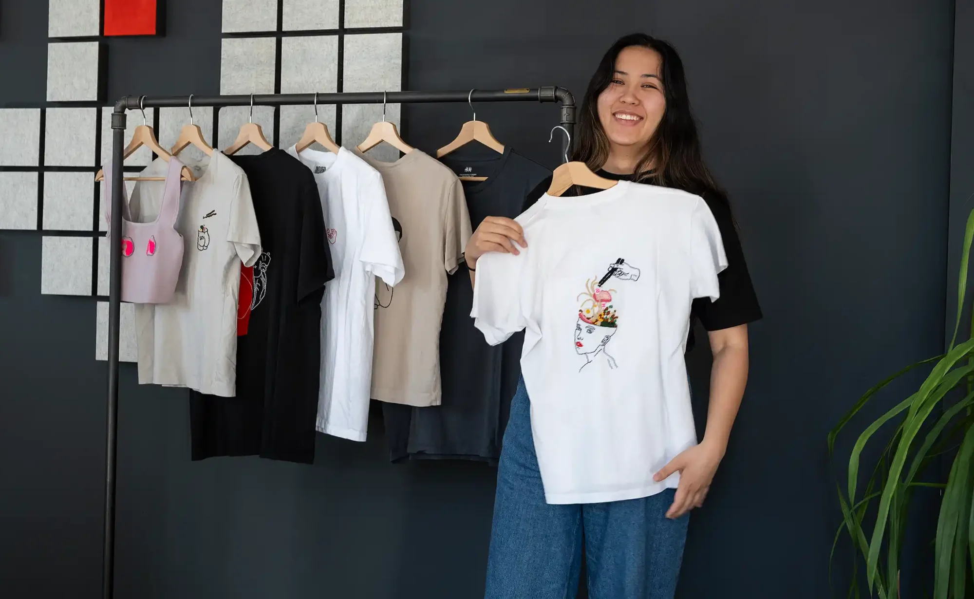 Desiree hält ihre bestickten T-Shirts hoch