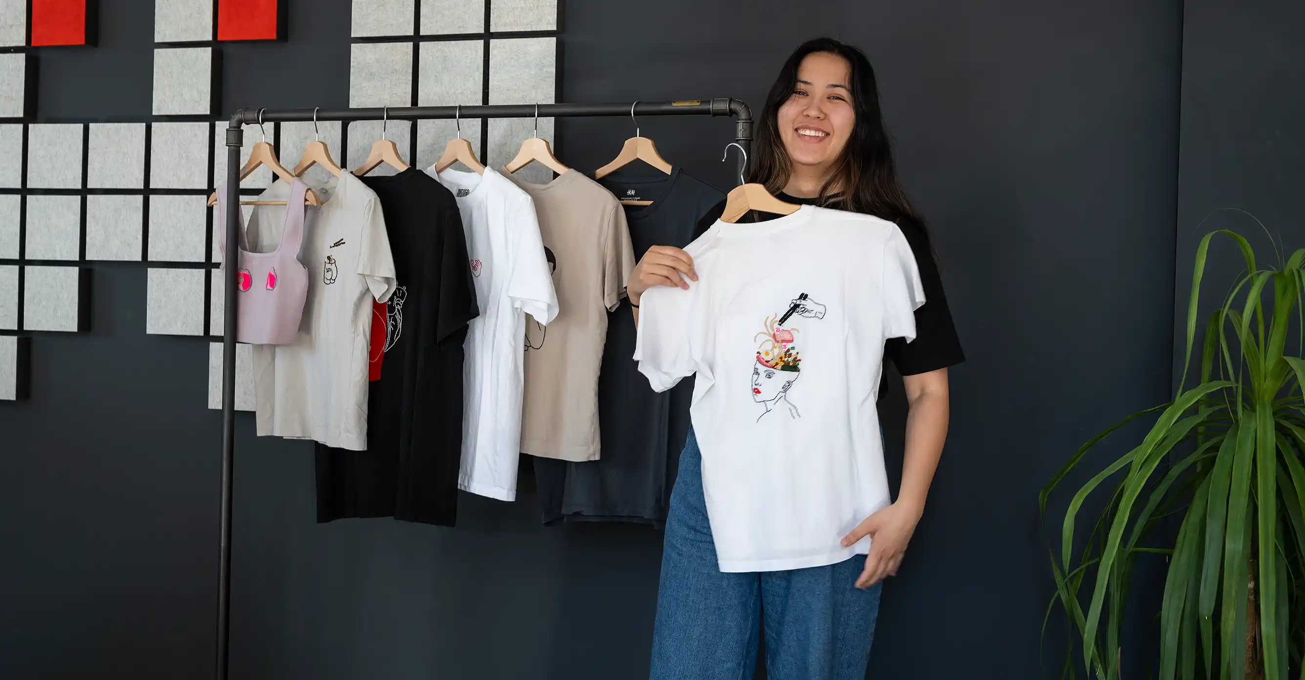 Desiree hält ihre bestickten T-Shirts hoch